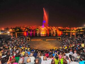 Espectadores reunidos en un anfiteatro al aire libre, admirando un espectáculo de fuentes iluminadas en Torrejón de Ardoz.