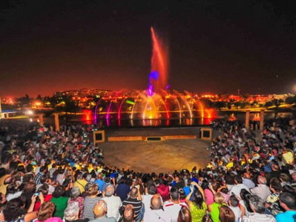 Espectadores reunidos en un anfiteatro al aire libre, admirando un espectáculo de fuentes iluminadas en Torrejón de Ardoz.