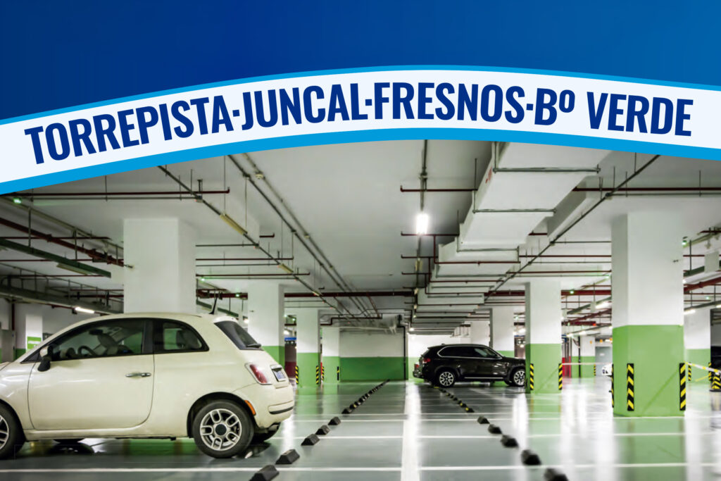 Interior de un aparcamiento con varias plazas, un coche blanco y un coche negro, en Torrejón de Ardoz.