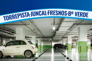 Interior de un aparcamiento con varias plazas, un coche blanco y un coche negro, en Torrejón de Ardoz.