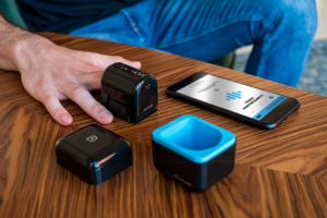 Dispositivo Glucube y móvil sobre una mesa de madera, junto a una mano y dos accesorios del aparato en Madrid.