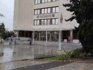 Vista exterior de los Juzgados de Plaza de Castilla, en un día lluvioso, donde se pueden ver personas entrando y saliendo del
