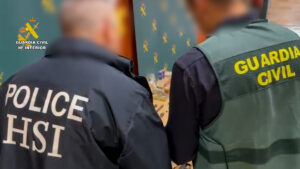 Agentes de la Guardia Civil y la policía observan objetos sobre una mesa, en un entorno de operación policial en Madrid.