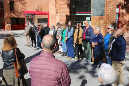 Grupo de personas en el exterior de un edificio, guardando un minuto de silencio, en Coslada (Madrid).