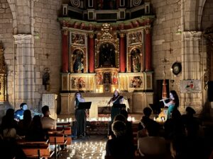 Un grupo de músicos se presenta en un concierto a la luz de las velas en un espacio interior con altarpieces elaborados. El p
