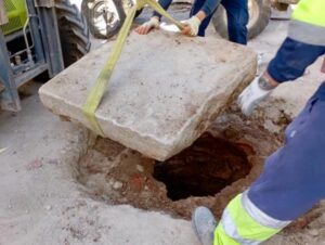 Operarios levantan una losa de piedra en las obras de la plaza de los Santos Niños de Alcalá de Henares