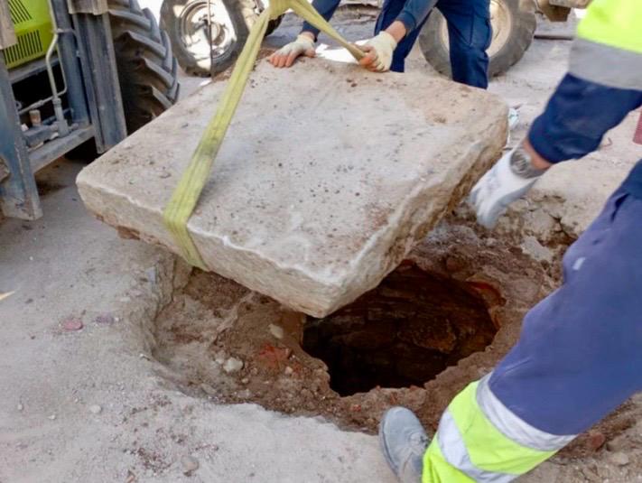 Operarios levantan una losa de piedra en las obras de la plaza de los Santos Niños de Alcalá de Henares